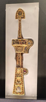 A narrow gold object with inlaid garnets